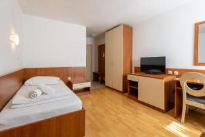 a bedroom with a bed and a desk with a tv at Hotel Porto in Zadar