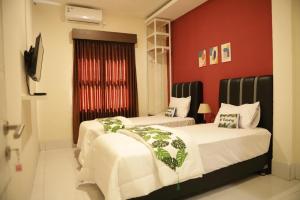 - 2 lits dans une chambre dotée d'un mur rouge dans l'établissement Tienery Guesthouse, à Tanjungkarang