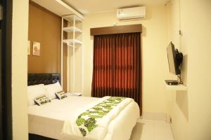 - une chambre avec un lit, une télévision et une fenêtre dans l'établissement Tienery Guesthouse, à Tanjungkarang