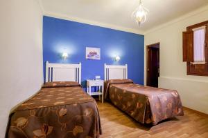 1 dormitorio con 2 camas y pared azul en Hostal El Caballo Blanco, en Osuna