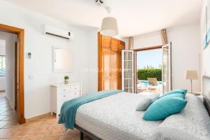 a bedroom with a bed with blue pillows at Villa BELLAVISTA in Arenal d'en Castell