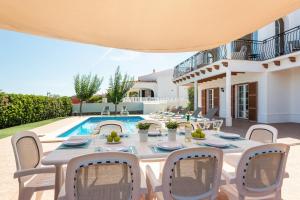 a patio with a table and chairs and a pool at Villa BELLAVISTA in Arenal d'en Castell