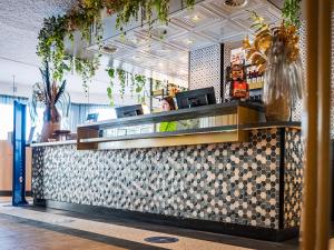 a woman sitting at a counter in a restaurant at Fletcher Hotel-Restaurant Scheveningen in Scheveningen