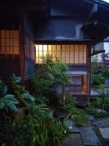 um edifício com um monte de plantas na frente dele em 旧鈴木邸 女性専用 em Matsuyama