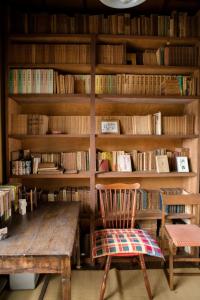 a library with a wooden table and a chair and books at 旧鈴木邸 女性専用 in Matsuyama