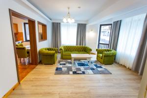 a living room with two green couches and a table at Pension Carmen`s Mansion A in Sinaia