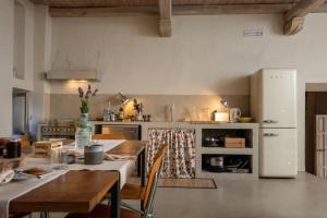 una cucina con tavolo e frigorifero bianco di La Casa della bifora / The House of the mullion a Sermoneta