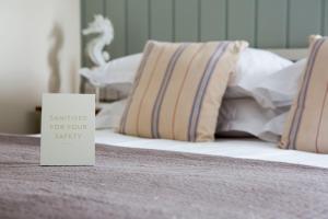 a white sign sitting on a bed with pillows at Seacroft in Holyhead