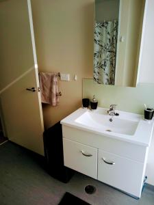 a bathroom with a white sink and a mirror at NORTH SHORE HOMESTAY Auckland in Auckland