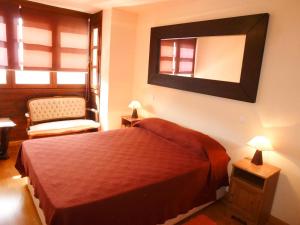 ein Schlafzimmer mit einem Bett, einem Spiegel und einem Stuhl in der Unterkunft Apartamentos Formigal - admite mascotas in Formigal