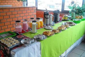 uma mesa verde com pastelarias e outros alimentos em HOTEL POUSADA OCEANO em Torres