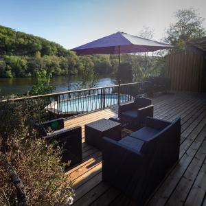 une terrasse avec des chaises, un parasol et une rivière dans l'établissement Un Havre de paix en bordure de la Dordogne, à Lalinde