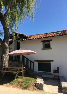 - une table de pique-nique avec un parasol en face d'une maison dans l'établissement La Grange d'Etxexuria, 