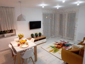 een woonkamer met een tafel en een tv bij Apartament Amber Comfort z prywatnym miejscem parkingowym in Kołobrzeg