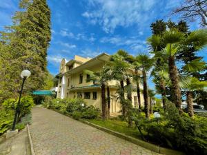 een huis met palmbomen aan de kant van een weg bij Rest-Matsesta Hotel in Sotsji