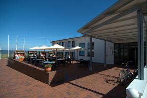 eine Terrasse mit Tischen, Stühlen und Sonnenschirmen in der Unterkunft Gästehaus Germania in Wangerooge