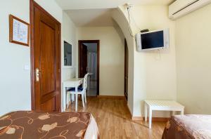 Habitación con cama, escritorio y TV. en Hostal El Caballo Blanco, en Osuna