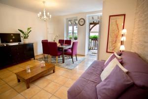 a living room with a purple couch and a table at Gite la Maison du Tonnelier in Comblanchien