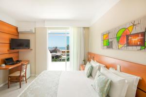 a bedroom with a bed and a desk and a window at Oceania Park Hotel Spa & Convention by RB Hotelaria in Florianópolis