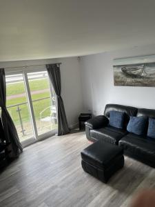 sala de estar con sofá negro y ventana grande en Beach Front Ground Floor Apartment, en Llanelli