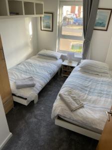 2 camas en una habitación con ventana en Beach Front Ground Floor Apartment en Llanelli