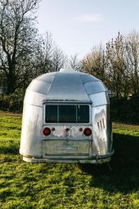 an old silver trailer parked in a field at Silver Airstream Glamping & Rental in Chichester