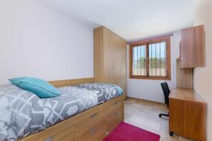 Schlafzimmer mit einem Bett, einem Schreibtisch und einem Fenster in der Unterkunft YourHouse Sa Raconada in Algaida