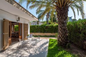 een patio met stoelen en een palmboom naast een huis bij YourHouse Casa Alcúdia Beach house in Alcudia