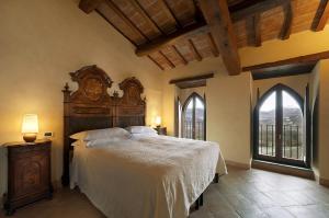 a bedroom with a large bed and two windows at Relais Monastero Di San Biagio in Nocera Umbra