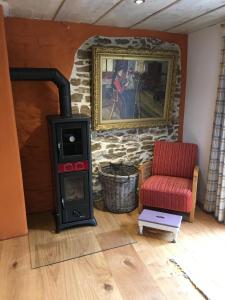a wood stove in a living room with a red chair at Ferienhaus Villa Kunnibunt in Burgsalach