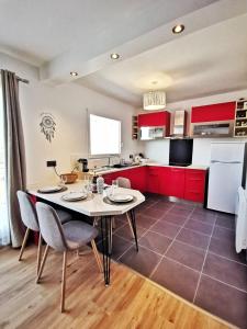 cocina con armarios rojos, mesa y sillas en Le 79 Reflet de la Marne, en Noisy-le-Grand