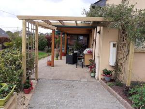 an entrance to a house with a wooden pergola at petit coin au calme in Baulon