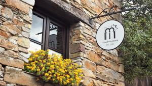 a sign on a brick building with a window and flowers at Fogar Mozárabe in Peñalba de Santiago