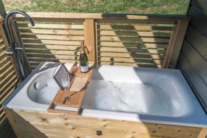 a bath tub with a sink and a bottle of wine at The Trossachs Collection in Kepculloch