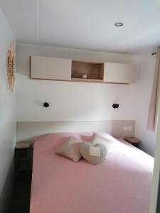 a bedroom with a pink bed with two pillows at Superbe Mobil home "excellence" au MAR ESTANG in Canet-en-Roussillon