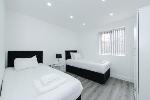 a white room with two beds and a window at Adbolton House Apartments - Sleek, Stylish, Brand New & Low Carbon in Nottingham