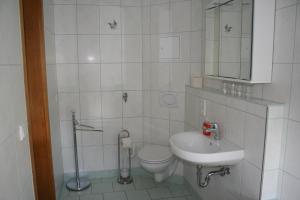 a white bathroom with a toilet and a sink at Gasthaus & Hotel Zur Linde in Hermsdorf