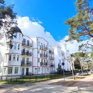 een wit gebouw met zwarte balkons in een straat bij Ferienwohnung Lieblingssuite am Strand in Ahlbeck