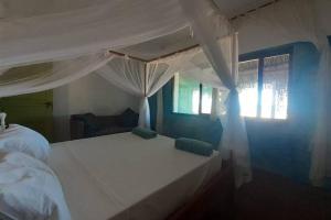 a bedroom with a white bed and a window at Casa Alegria Tofo Beach in Inhambane