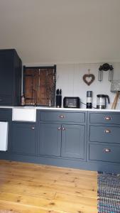 a kitchen with blue cabinets and a white sink at The cosy hut in Faversham