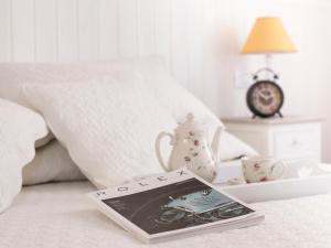 a book on a bed with a tea pot and a clock at Lungomare Rooms & Charme in La Spezia