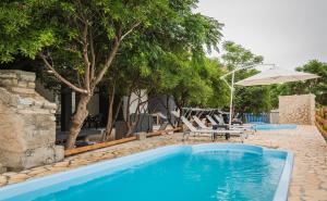 a swimming pool with chairs and an umbrella at Apartmani Mabele in Pag