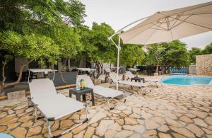 a patio with chairs and an umbrella next to a pool at Apartmani Mabele in Pag