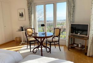 een woonkamer met een tafel en stoelen en een televisie bij B&B Domaine En Trembley in Commugny