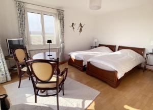 1 dormitorio con 2 camas, mesa y sillas en B&B Domaine En Trembley, en Commugny