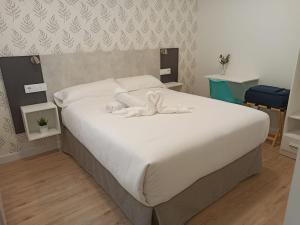 1 dormitorio con 1 cama grande con sábanas blancas en Apartamentos Adarve, en Ciudad Rodrigo