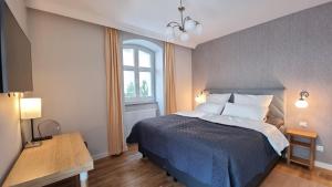 a bedroom with a bed with a blue blanket and a window at Apartamenty Świnoujście - Wisus in Świnoujście