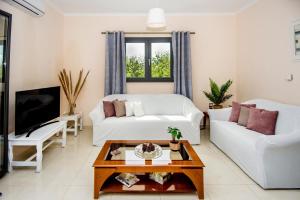 a living room with a white couch and a tv at Aella Apartment in Skala Kefalonias