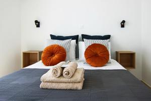 a bed with two towels and two orange pillows at Phaedrus Living: Seaside Luxury Flat Lighthouse 62 in Paphos