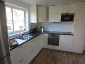 uma cozinha com armários brancos, um lavatório e uma janela em TORPET (Villa Solsidan), Hälsingland, Sweden em Arbrå
